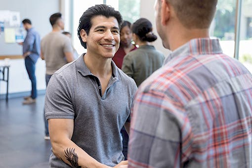 Two men shaking hands at a cancer support group meeting.