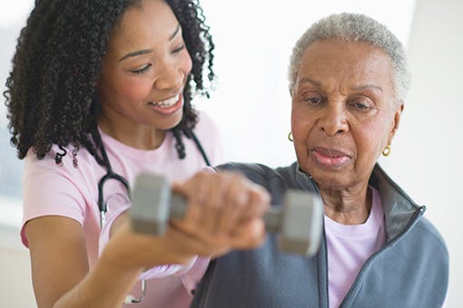 A physical therapist helping an elderly cancer patient with exercises.
